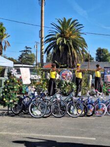 People performing near decorated bikes and trees.