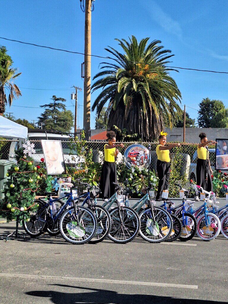 People performing near decorated bikes and trees.