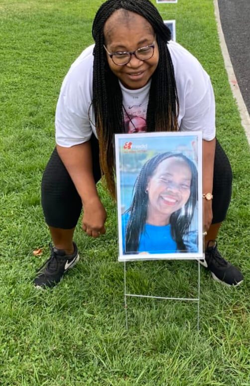 Person crouching next to framed outdoor photo.