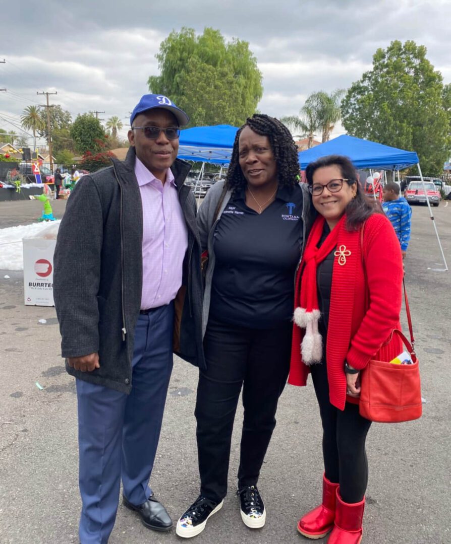 Three people smiling at outdoor event.