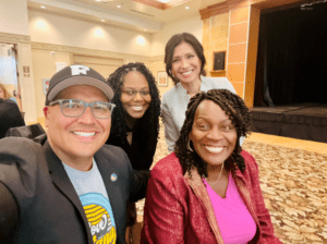 Group of four people smiling indoors.