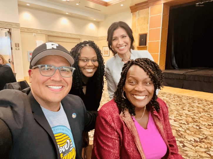 Group of four people smiling indoors.