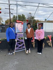 Three people standing by a decorated easel.