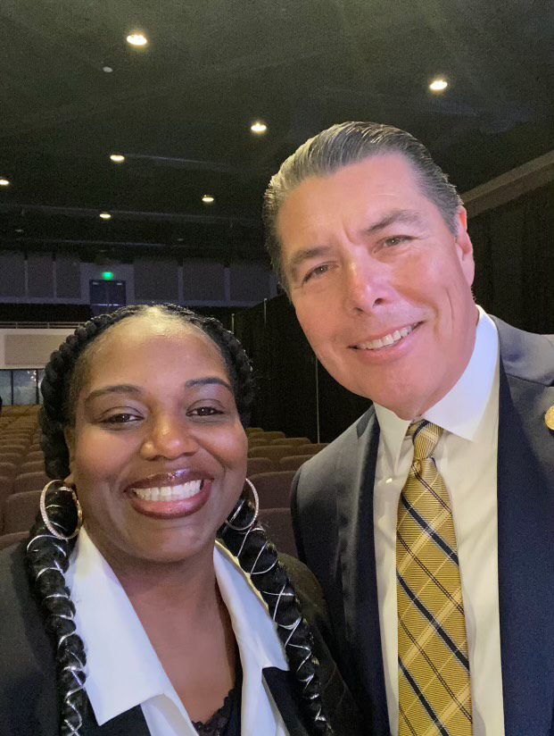Two people smiling in a conference setting.